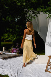 Jupe longue fluide doublée jaune portée par une femme, vue de dos, drapés, jupe jaune
