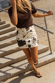 Jupe courte à motifs vache portée par une femme, en marchant, escalier, main sur la rampe