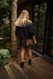 Jupe satinée à dentelle portée par une femme, vue de dos, forêt, bottines