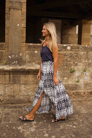 Jupe longue tie-dye fendue portée par une femme, en marchant, mur en pierre, imprimé tie-dye