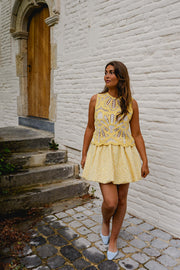 Jupe boule doublée portée par une femme, avec un haut jaune à motifs, porte en bois