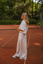 Jupe longue coupe droite portée par une femme, vue de trois-quarts, filet de tennis, de profil