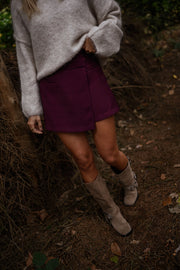 Jupe-short zippée sur le côté porté par une femme, vue rapprochée, pull beige, jupe-short bordeaux