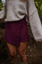 Jupe-short zippée sur le côté porté par une femme, vue rapprochée, jupe-short bordeaux, pull beige