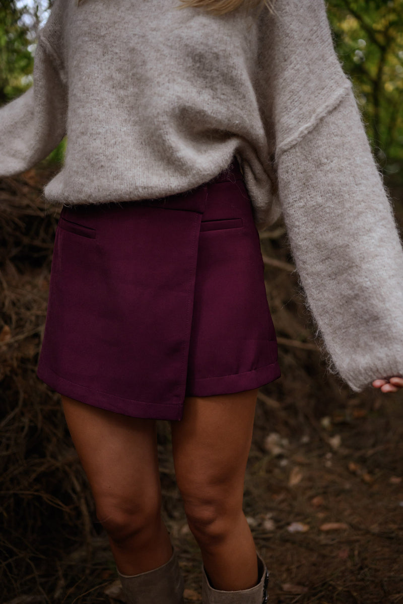 Jupe-short zippée sur le côté porté par une femme, vue rapprochée, jupe-short bordeaux, pull beige