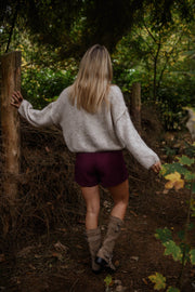 Jupe-short zippée sur le côté porté par une femme, vue de dos, forêt, bottes