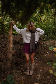 Jupe-short zippée sur le côté porté par une femme, silhouette entière, écharpe grise, tronc d'arbre