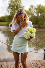 Jupe-short courte à fermeture latérale porté par une femme, silhouette entière, étang, bouquet