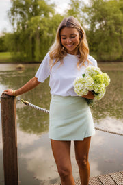 Jupe-short courte à fermeture latérale porté par une femme, silhouette entière, ponton en bois, bouquet