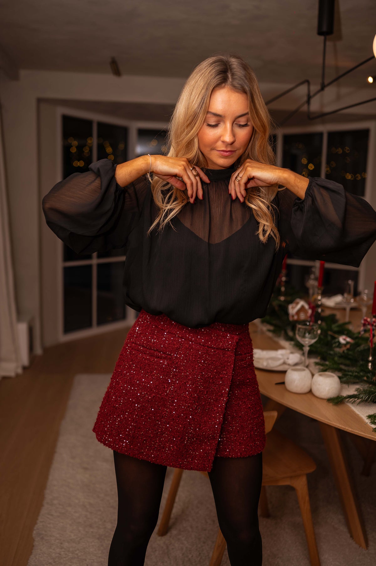 Jupe-short en tweed brillant bordeaux porté par une femme, vue de trois-quarts, blouse noire, table dressée