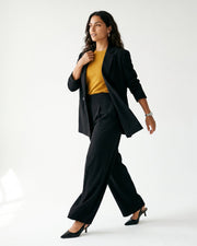 Blazer croisé à coupe ajustée porté par une femme, silhouette entière, pantalon noir, fond blanc