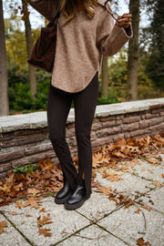 Legging moulant à fente porté par une femme, silhouette entière, pull beige, bottines