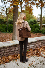 Legging moulant à fente porté par une femme, vue de dos, sac marron, pull beige