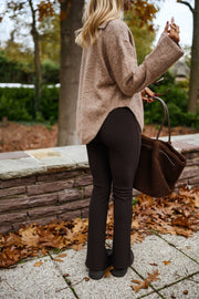 Legging moulant à fente porté par une femme, silhouette entière, muret, sac marron