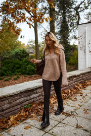 Legging moulant à fente porté par une femme, silhouette entière, pull beige, feuilles