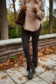 Legging moulant à fente porté par une femme, silhouette entière, sac marron, pull beige