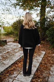 Legging moulant fendu porté par une femme, vue de dos, veste noire, feuilles