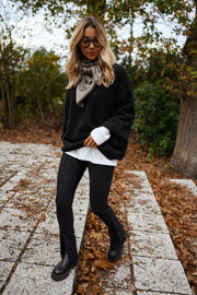 Legging moulant fendu porté par une femme, vue de trois-quarts, veste noire, escalier