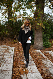Legging moulant fendu porté par une femme, silhouette entière, veste noire, arbres