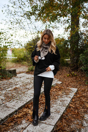 Legging moulant fendu porté par une femme, silhouette entière, veste noire, foulard