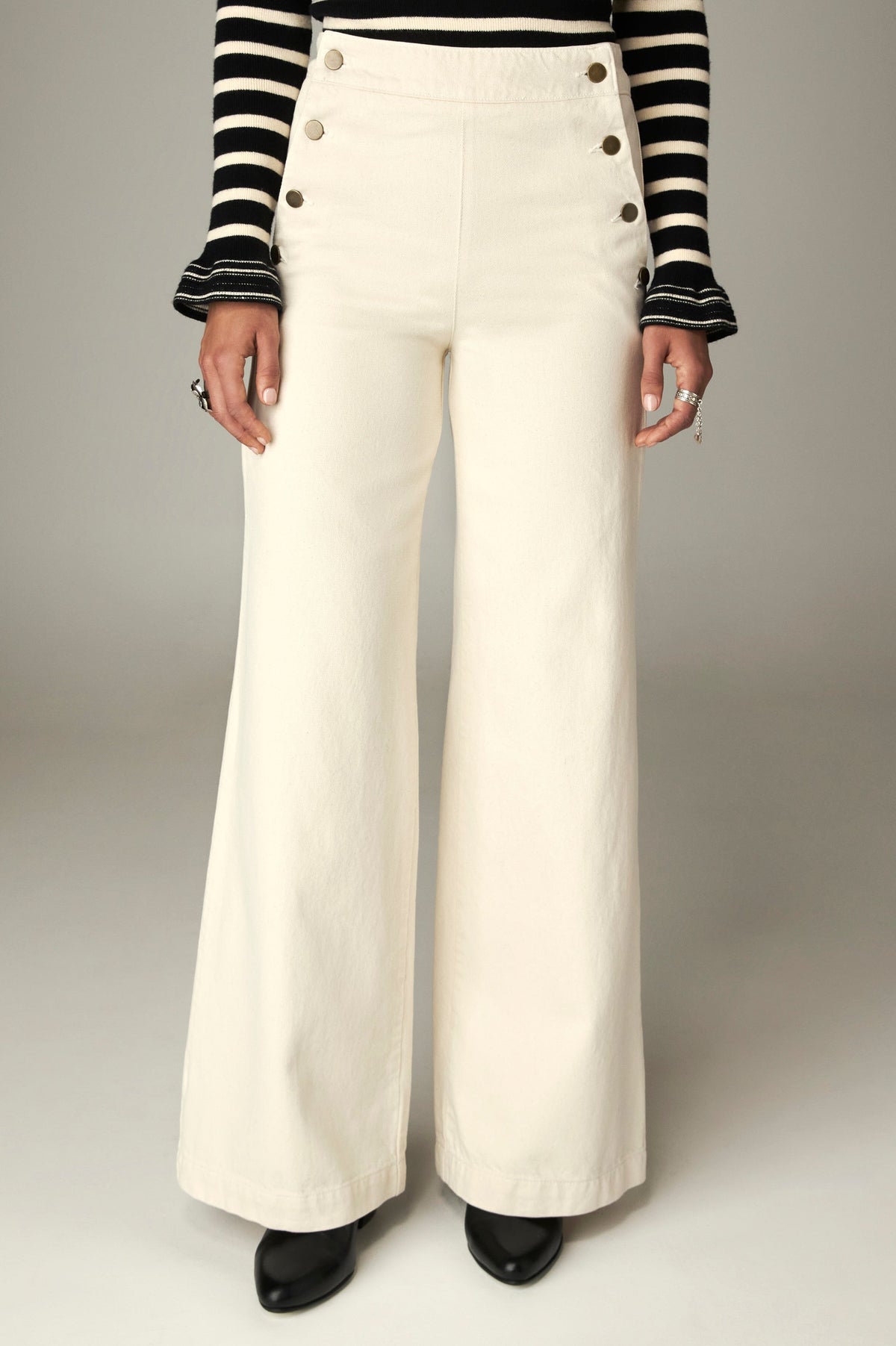 Pantalon écru à taille haute, boutons latéraux et jambes larges, vue de face
