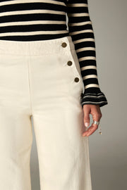 Détail de trois quarts de la taille et des boutons du pantalon écru
