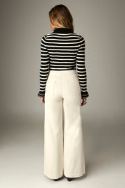 Pantalon écru porté de dos en pied avec un pull rayé