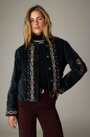 Veste sombre à bordures brodées et poches plaquées, portée de face.