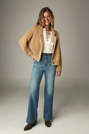 Cardigan maille col revers — vue portée en pied, regard baissé