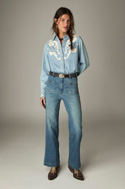 Chemise bleu clair à motifs crème portée de face en pied avec un jean