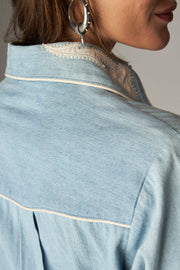 Détail arrière du col décoré et de l'empiècement à passepoil de la chemise bleu clair