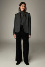 Silhouette portant une veste gris foncé à fines rayures et un pantalon noir.