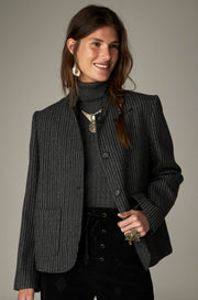 Veste gris foncé à fines rayures verticales, boutons et poches devant, portée de face.