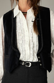 Gilet noir encolure en V — gros plan torse, gilet, blouse à volants et ceinture