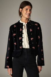 Veste noire à fleurs roses et bas plissé, portée ouverte de face.