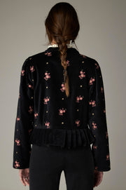 Veste noire à fleurs roses, manches longues et bas plissé, vue de dos.