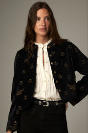 Veste noire à motifs dorés et poches brodées, portée ouverte de face.