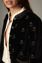 Détail du col brodé, des boutons et des petits motifs dorés de la veste noire.