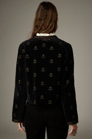Dos de la veste noire à petits motifs dorés et bordures brodées au col et aux poignets.