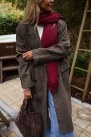 Manteau long doublé à épaulettes taupe porté par une femme, vue rapprochée, écharpe bordeaux, sac noir