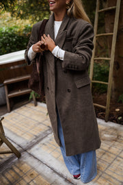Manteau long doublé à épaulettes taupe porté par une femme, vue de face, terrasse, échelle