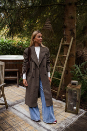 Manteau long doublé à épaulettes taupe porté par une femme, vue de trois-quarts, terrasse, lanterne
