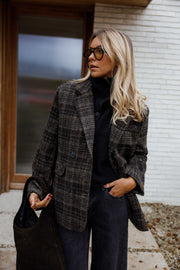 Manteau à carreaux doublé porté par une femme, vue de trois-quarts, mur blanc, lunettes de soleil