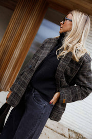 Manteau à carreaux doublé porté par une femme, vue rapprochée, col roulé noir, lunettes de soleil