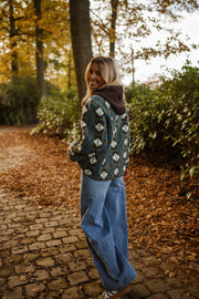Manteau polaire à capuche amovible porté par une femme, vue de dos, allée pavée, jean bleu