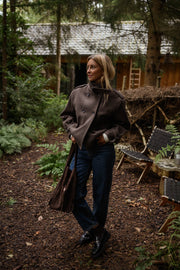 Manteau doublé à revers montant marron porté par une femme, vue de trois-quarts, sous-bois, jean bleu