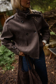 Manteau doublé à revers montant marron porté par une femme, vue rapprochée, manteau marron, main dans la poche