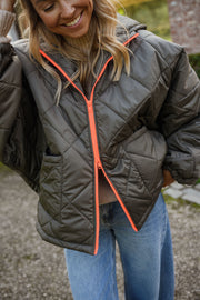 Manteau imperméable matelassé kaki porté par une femme, vue rapprochée, matelassé, fermeture orange