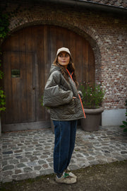 Manteau imperméable matelassé kaki porté par une femme, vue de face, porte cintrée, casquette beige
