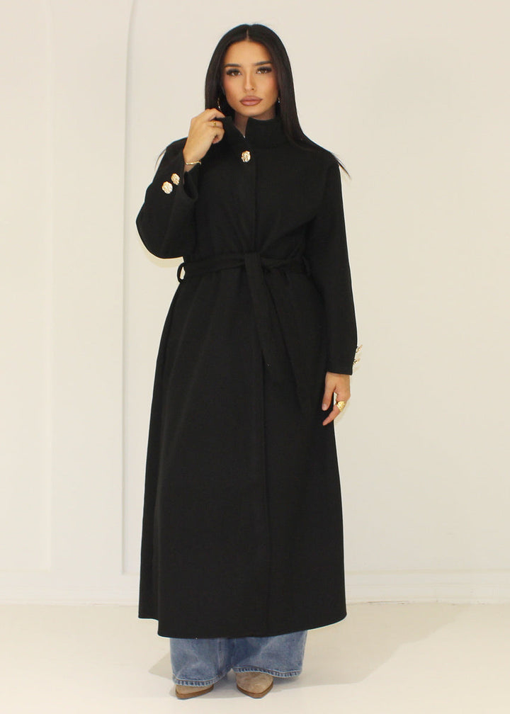Manteau long noir à col montant — vue en pied.